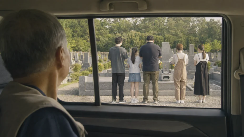 墓参りをする家族を、少し離れた車の中から見守る父を表現したAI生成イメージ